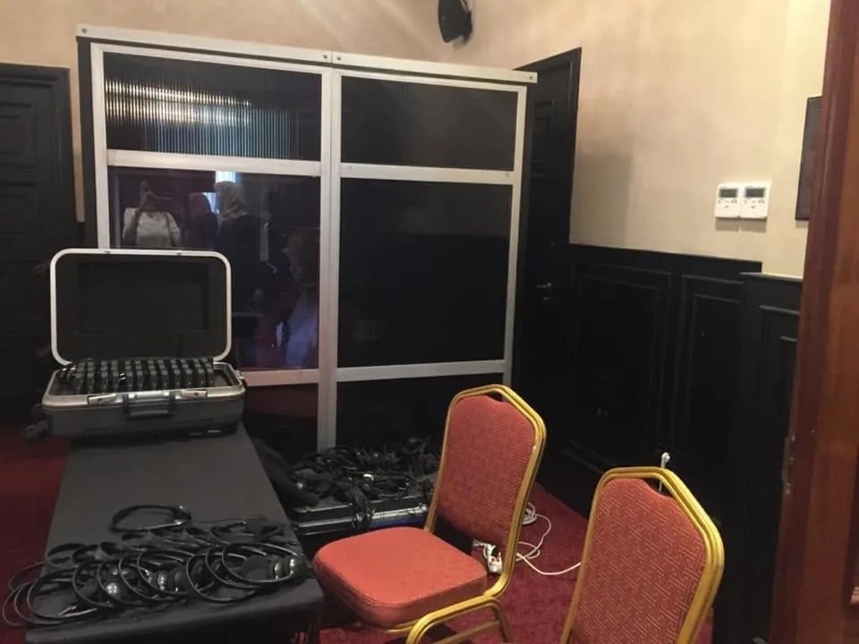 Cabine d'interprétation mobile avec valise de récepteurs et casques à l'entrée d'une salle