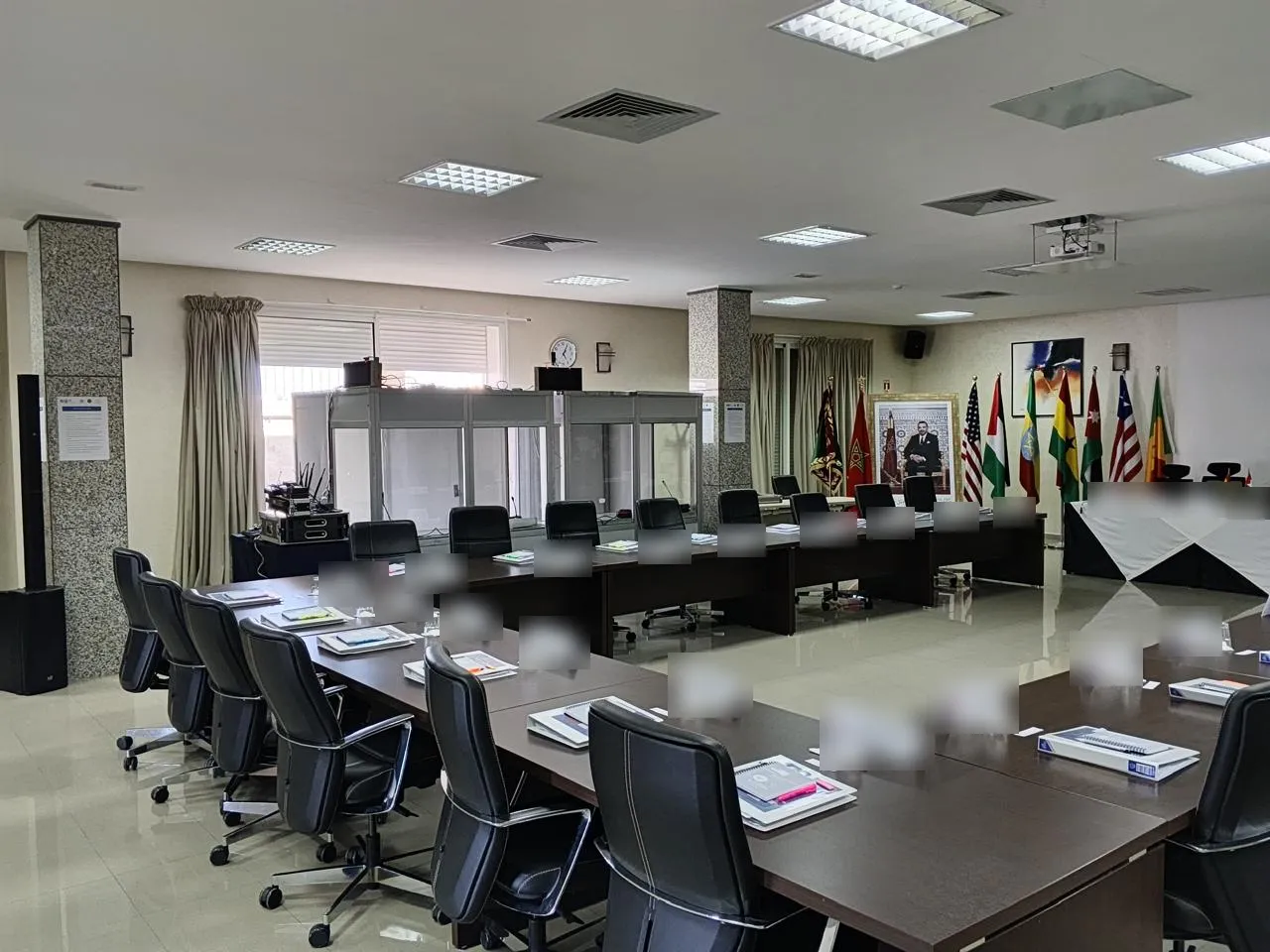 Salle de réunion en U avec cabines d'interprétation et drapeaux de plusieurs pays