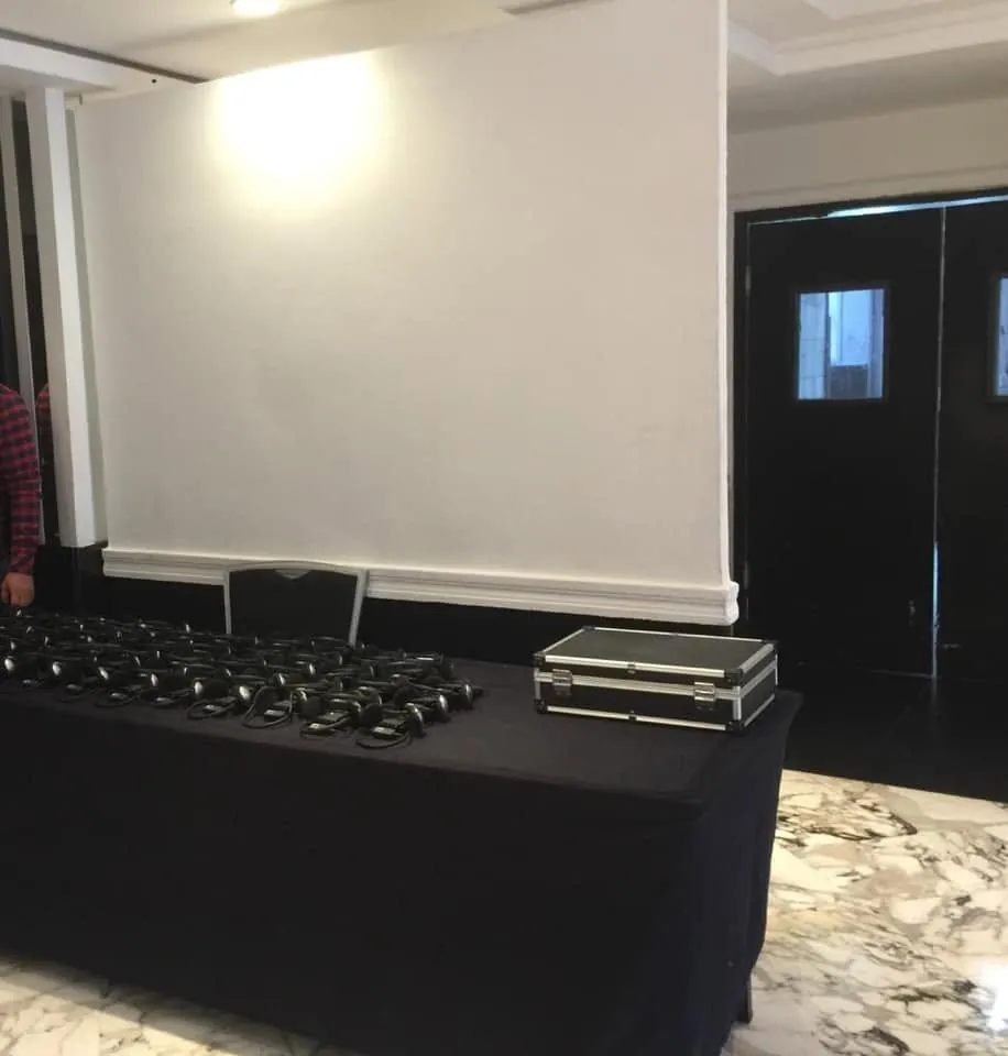 Casques et récepteurs alignés sur une table à l'entrée d'une salle de conférence